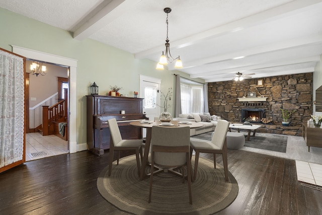 dining area with a fireplace, beamed ceiling, wood-type flooring, and a textured ceiling