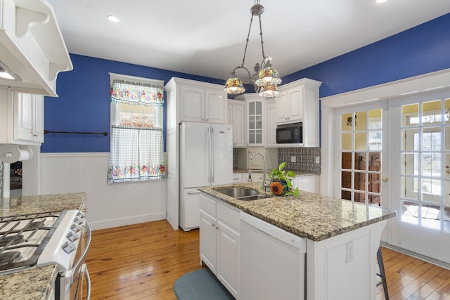 kitchen with sink, white appliances, a center island with sink, white cabinets, and light wood-type flooring