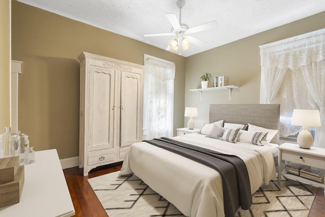 bedroom with ceiling fan, dark wood-type flooring, and a textured ceiling