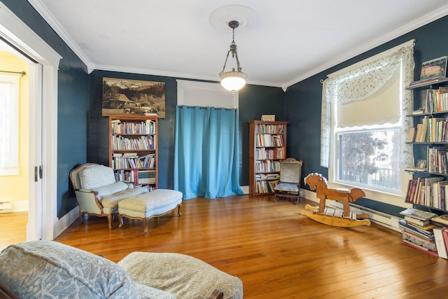 sitting room featuring wood-type flooring, crown molding, and a baseboard heating unit