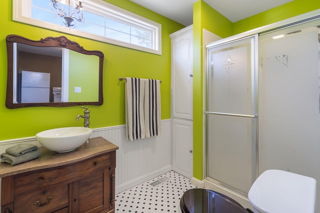 bathroom featuring vanity, toilet, walk in shower, and an inviting chandelier