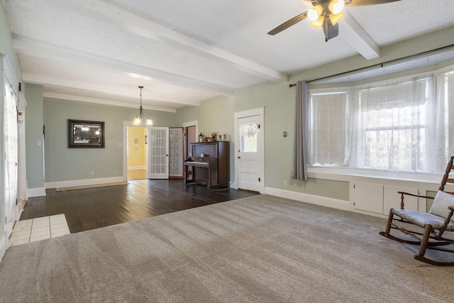 unfurnished living room featuring beam ceiling, ceiling fan with notable chandelier, and dark wood-type flooring