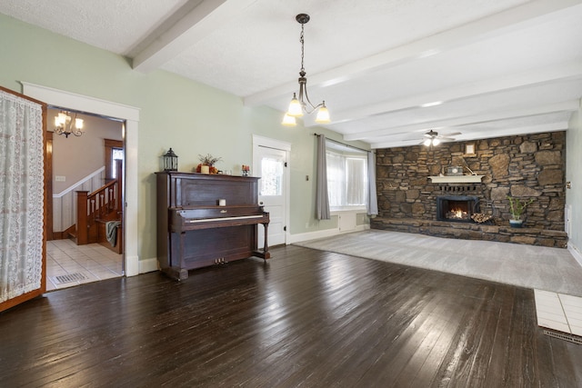 living room with beamed ceiling, wood-type flooring, a textured ceiling, a fireplace, and ceiling fan with notable chandelier