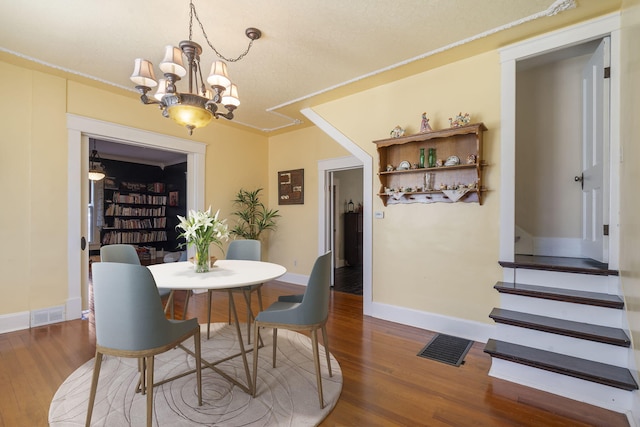 dining space with crown molding, a notable chandelier, and hardwood / wood-style flooring