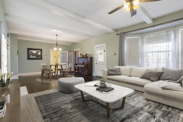 living room with beamed ceiling, ceiling fan with notable chandelier, and dark wood-type flooring