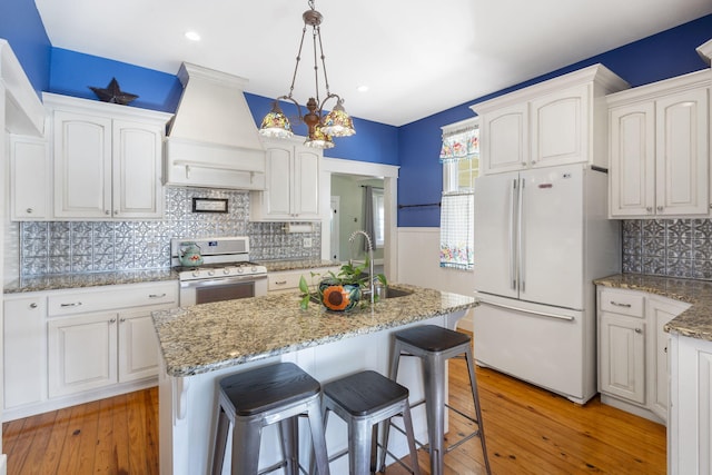 kitchen featuring white refrigerator, white cabinetry, and range with gas cooktop