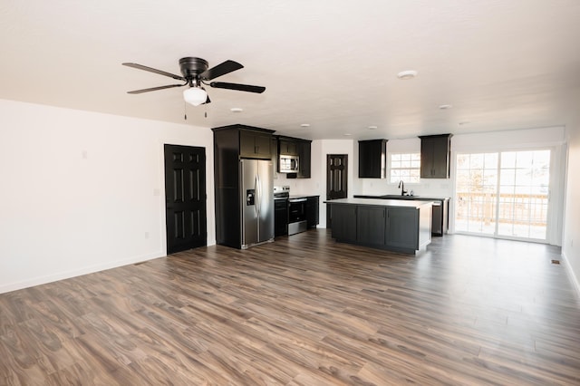 unfurnished living room with ceiling fan, dark wood-type flooring, and sink