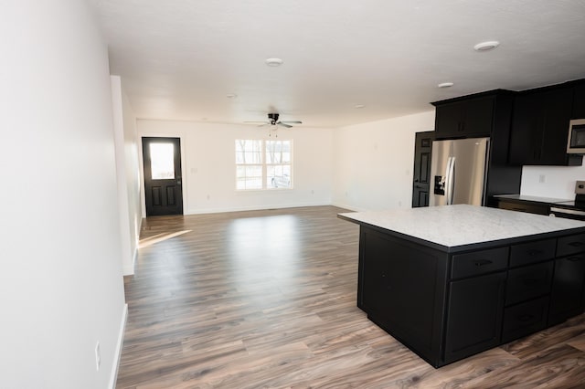 kitchen with ceiling fan, hardwood / wood-style floors, a kitchen island, and appliances with stainless steel finishes