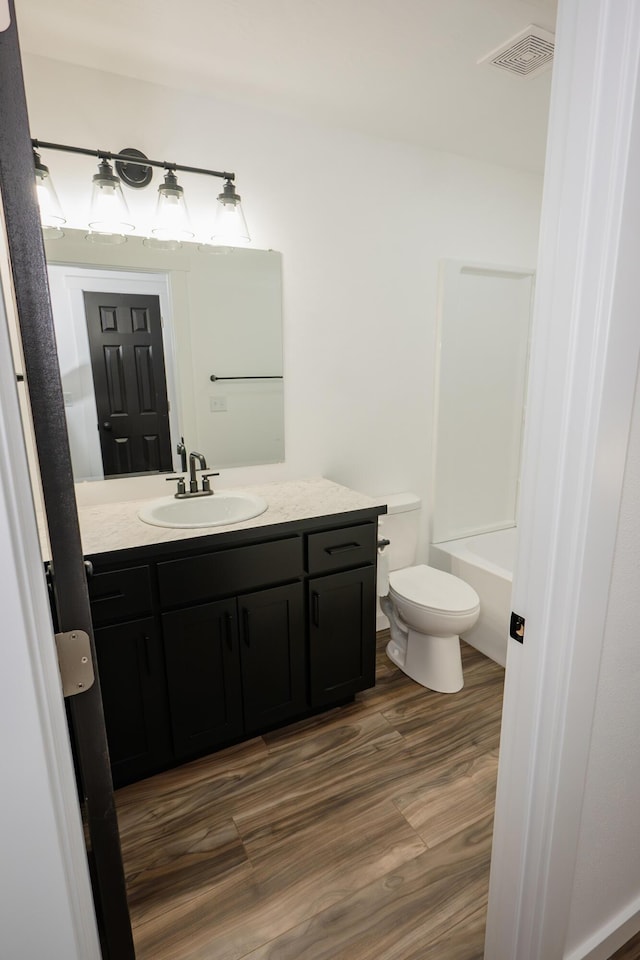 bathroom with hardwood / wood-style flooring, vanity, and toilet