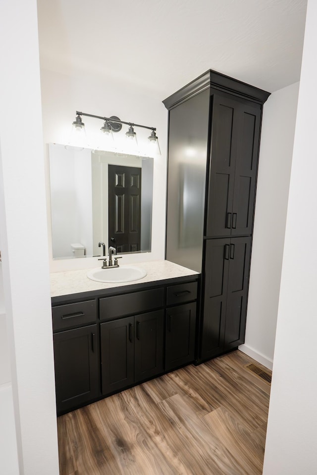 bathroom with toilet, vanity, and hardwood / wood-style flooring