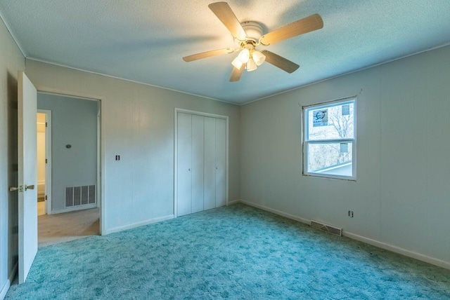 unfurnished bedroom featuring a textured ceiling, ceiling fan, light carpet, and a closet