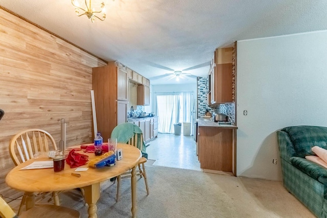 dining area with a textured ceiling, wooden walls, and sink