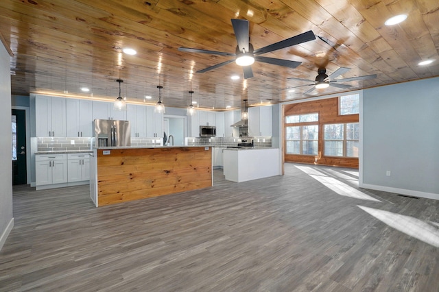 kitchen with white cabinets, hanging light fixtures, appliances with stainless steel finishes, tasteful backsplash, and a kitchen island