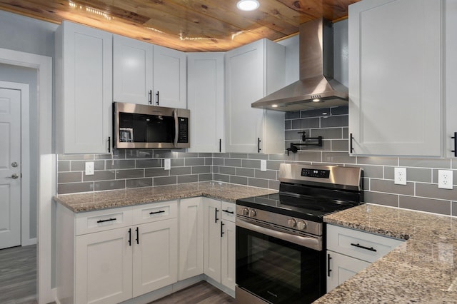 kitchen featuring white cabinetry, wall chimney exhaust hood, stainless steel appliances, and light stone countertops