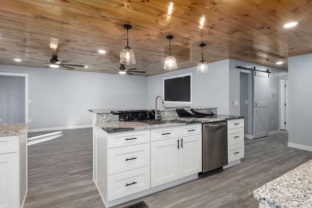 kitchen with a barn door, white cabinetry, pendant lighting, and stainless steel dishwasher