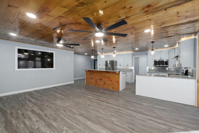 kitchen featuring appliances with stainless steel finishes, a center island, light stone counters, white cabinets, and decorative light fixtures