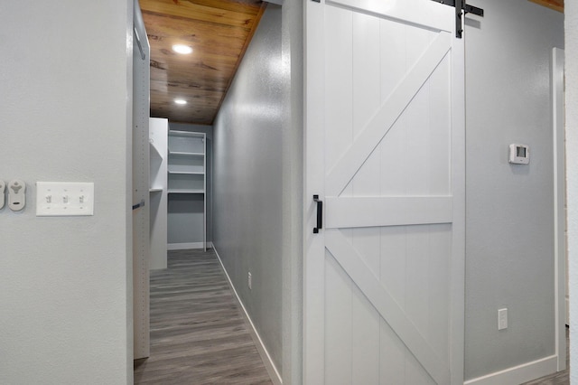 corridor with dark hardwood / wood-style floors, a barn door, and wooden ceiling