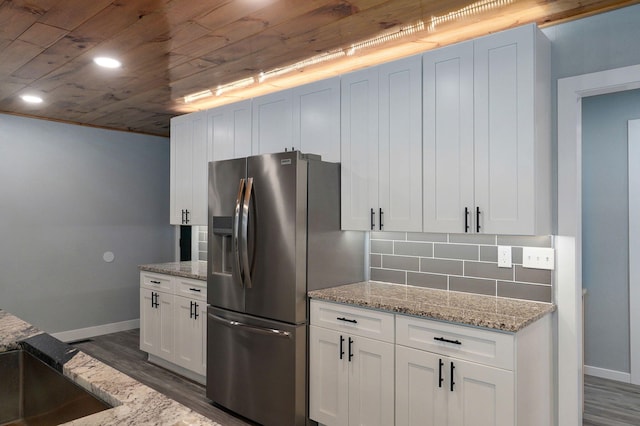 kitchen featuring tasteful backsplash, light stone countertops, white cabinets, and stainless steel fridge with ice dispenser