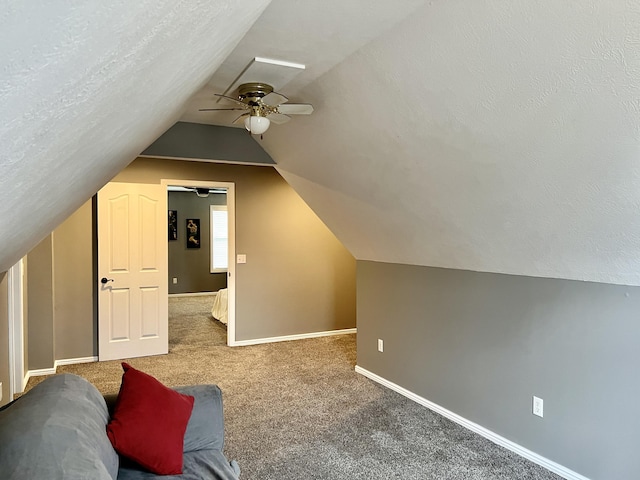 bonus room featuring lofted ceiling, carpet, a textured ceiling, and ceiling fan