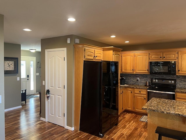 kitchen with black appliances, dark hardwood / wood-style flooring, dark stone countertops, and tasteful backsplash