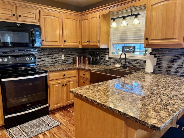 kitchen with sink, backsplash, dark stone countertops, light hardwood / wood-style floors, and black appliances