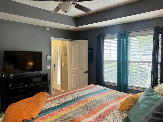 bedroom with ceiling fan and a tray ceiling