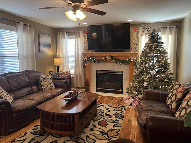 living room with ceiling fan, a tile fireplace, and light hardwood / wood-style flooring