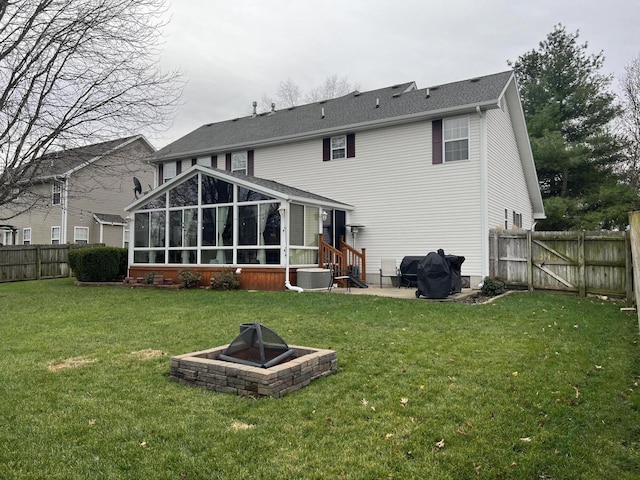 back of property featuring a lawn, a sunroom, and a fire pit