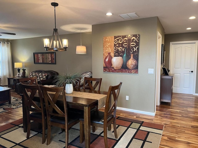 dining room with ceiling fan with notable chandelier and hardwood / wood-style flooring