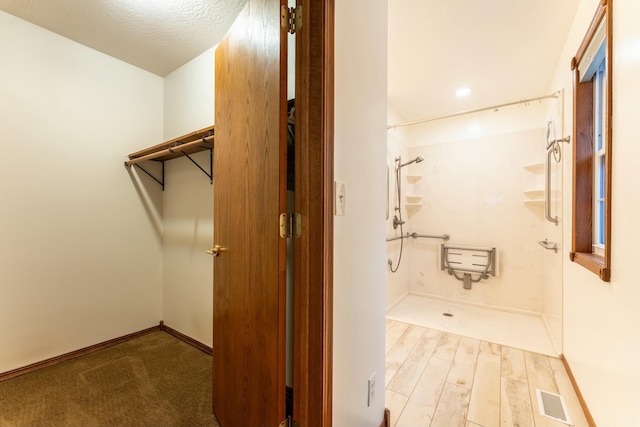 bathroom featuring hardwood / wood-style floors, a shower, and a textured ceiling