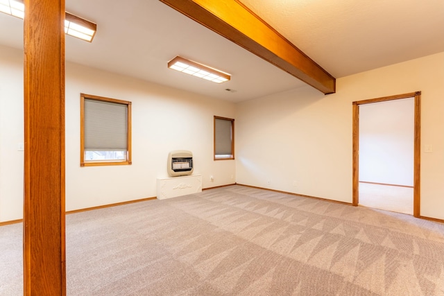 unfurnished room with beamed ceiling, light colored carpet, and heating unit