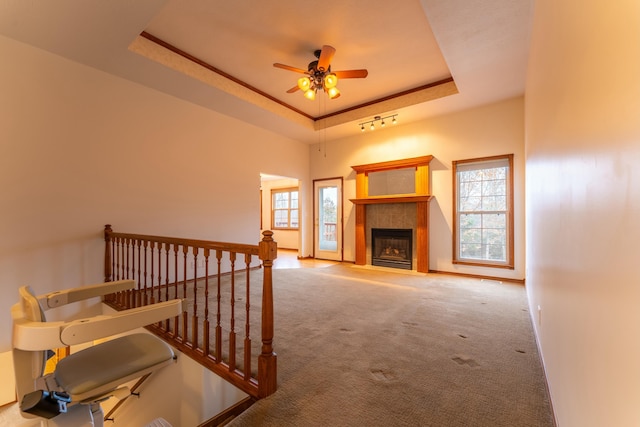 carpeted living room featuring a fireplace, a raised ceiling, and ceiling fan