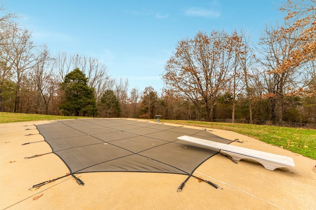 view of pool featuring a lawn and a diving board