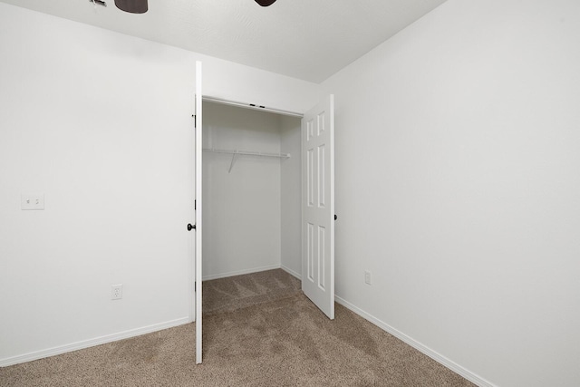 unfurnished bedroom featuring ceiling fan, a closet, and carpet floors