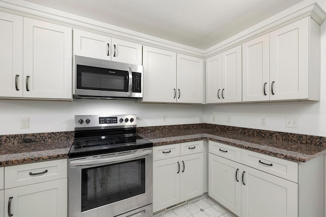 kitchen with white cabinets, dark stone counters, and appliances with stainless steel finishes