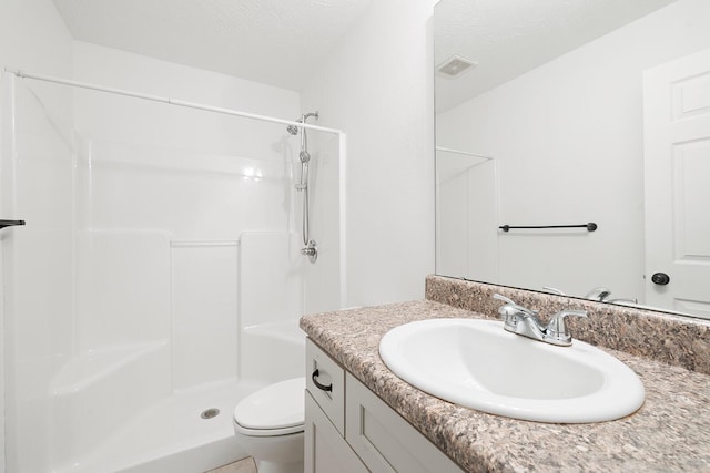 bathroom featuring a shower, vanity, a textured ceiling, and toilet