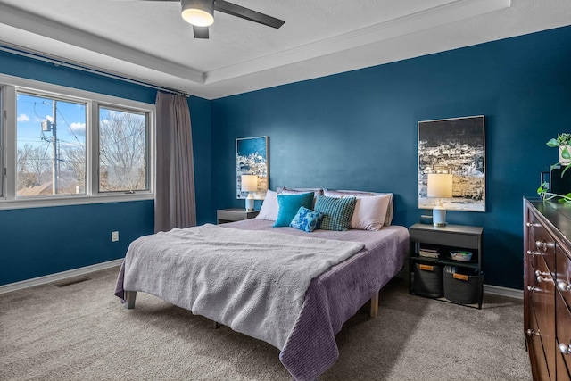 carpeted bedroom with a tray ceiling and ceiling fan