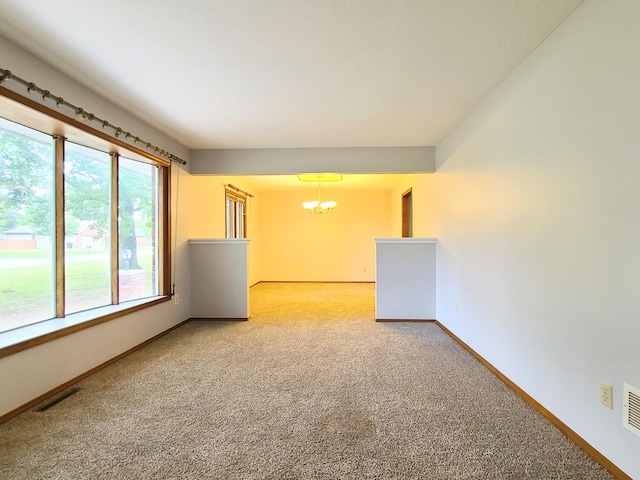 carpeted empty room featuring a notable chandelier