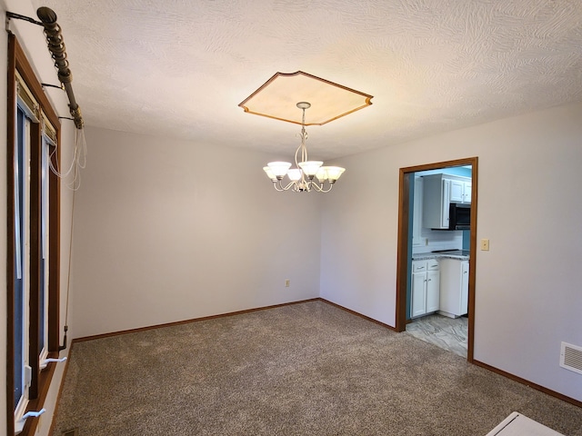 carpeted empty room featuring an inviting chandelier and a textured ceiling