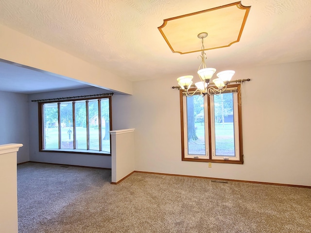 empty room featuring carpet flooring, a textured ceiling, and a notable chandelier