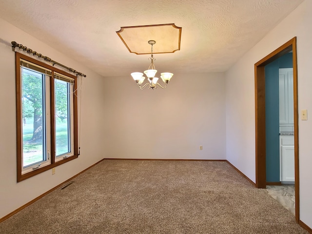 unfurnished room with light colored carpet, a notable chandelier, and a textured ceiling