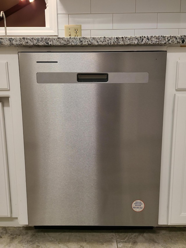 interior details with stainless steel dishwasher, light stone countertops, and white cabinets