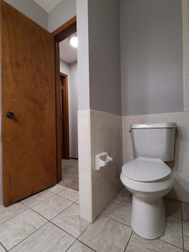 bathroom featuring toilet and tile walls