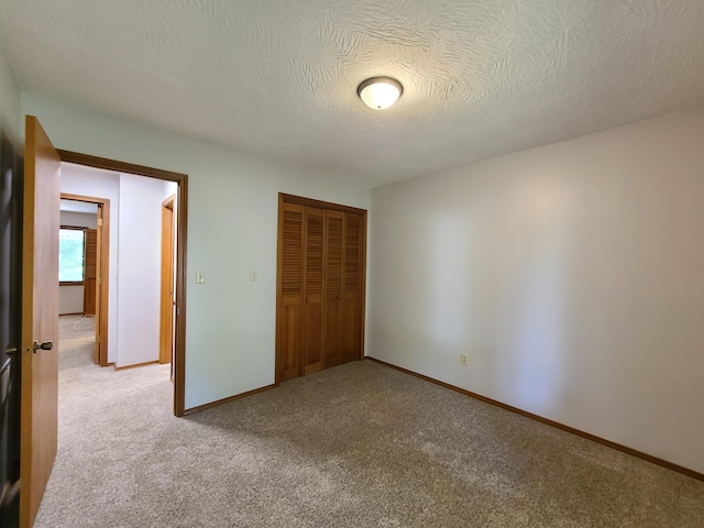 unfurnished bedroom with light colored carpet, a closet, and a textured ceiling