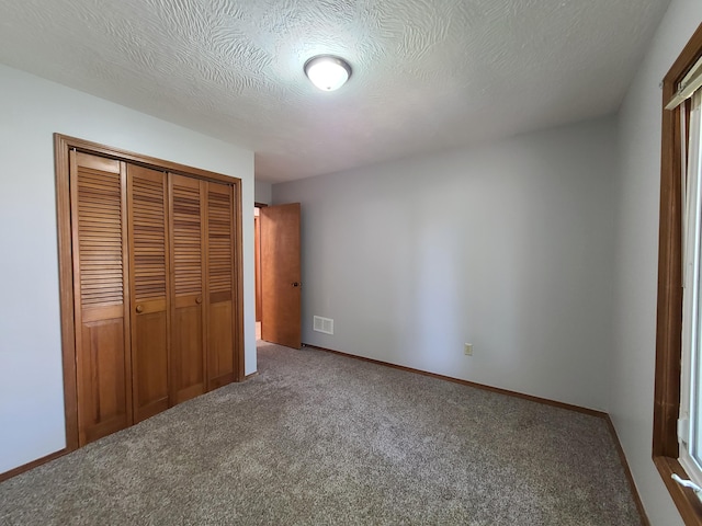 unfurnished bedroom featuring a closet, a textured ceiling, and carpet