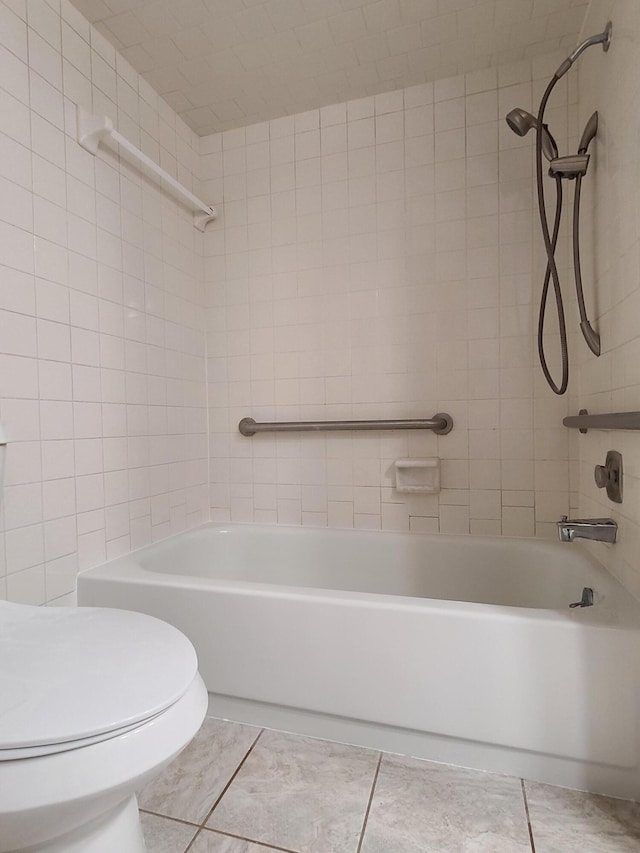 bathroom featuring tile patterned floors, toilet, and tiled shower / bath combo