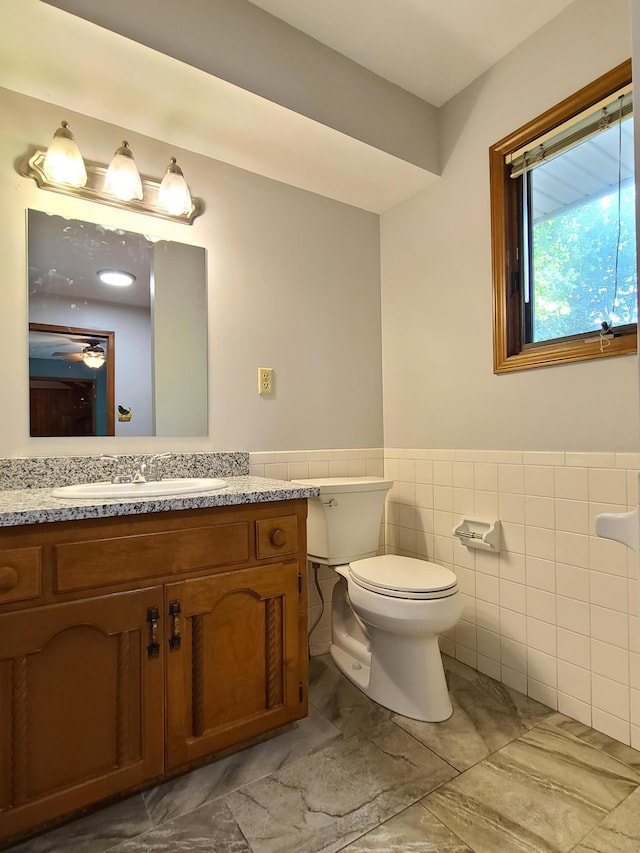 bathroom featuring vanity, toilet, and tile walls