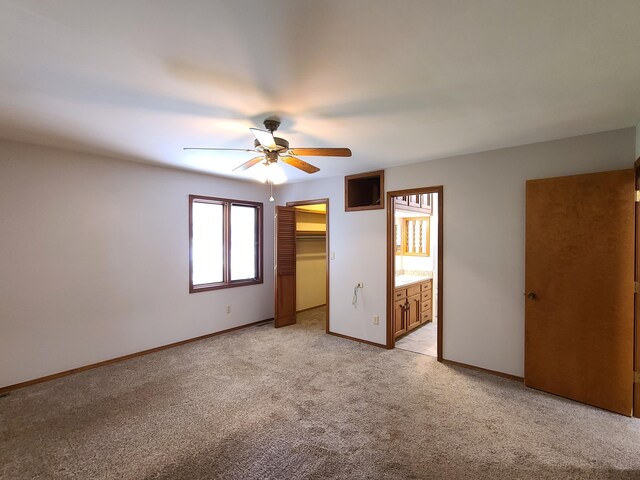 unfurnished bedroom with a walk in closet, ceiling fan, light carpet, ensuite bath, and a closet