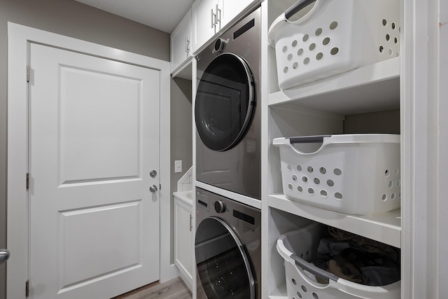 laundry area featuring cabinets, light hardwood / wood-style floors, and stacked washer and clothes dryer