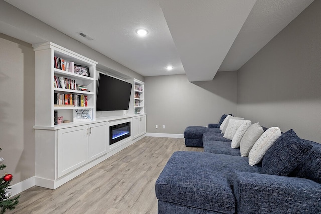 living room with built in shelves and light hardwood / wood-style floors